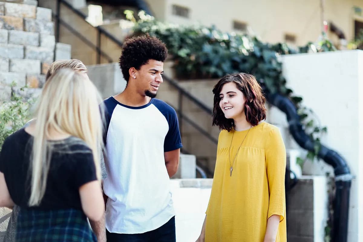 Three young people chatting and smiling outdoors