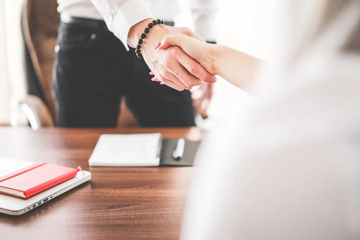 Two professionals shaking hands across an office desk